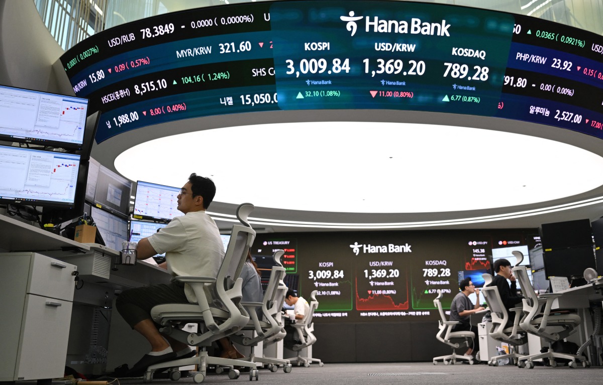 Currency dealers monitor exchange rates beneath a big screen showing South Korea's benchmark stock index (KOSPI) and the Korean won/USD exchange rate in a foreign exchange dealing room at the Hana Bank headquarters in Seoul on June 20, 2025. Photo by Jung Yeon-je / AFP.
