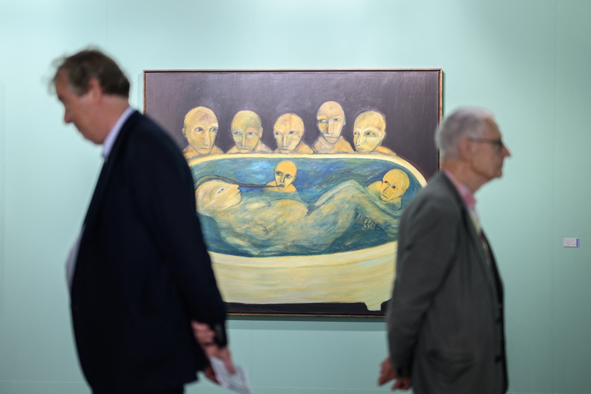 Visitors stand next to 'Die Wachter, 1990/1', a work by Swiss artist Annette Barcelo, on display at the Unlimited section of the Art Basel modern and contemporary art fair in Basel, on June 17, 2025. Photo by Fabrice COFFRINI / AFP.