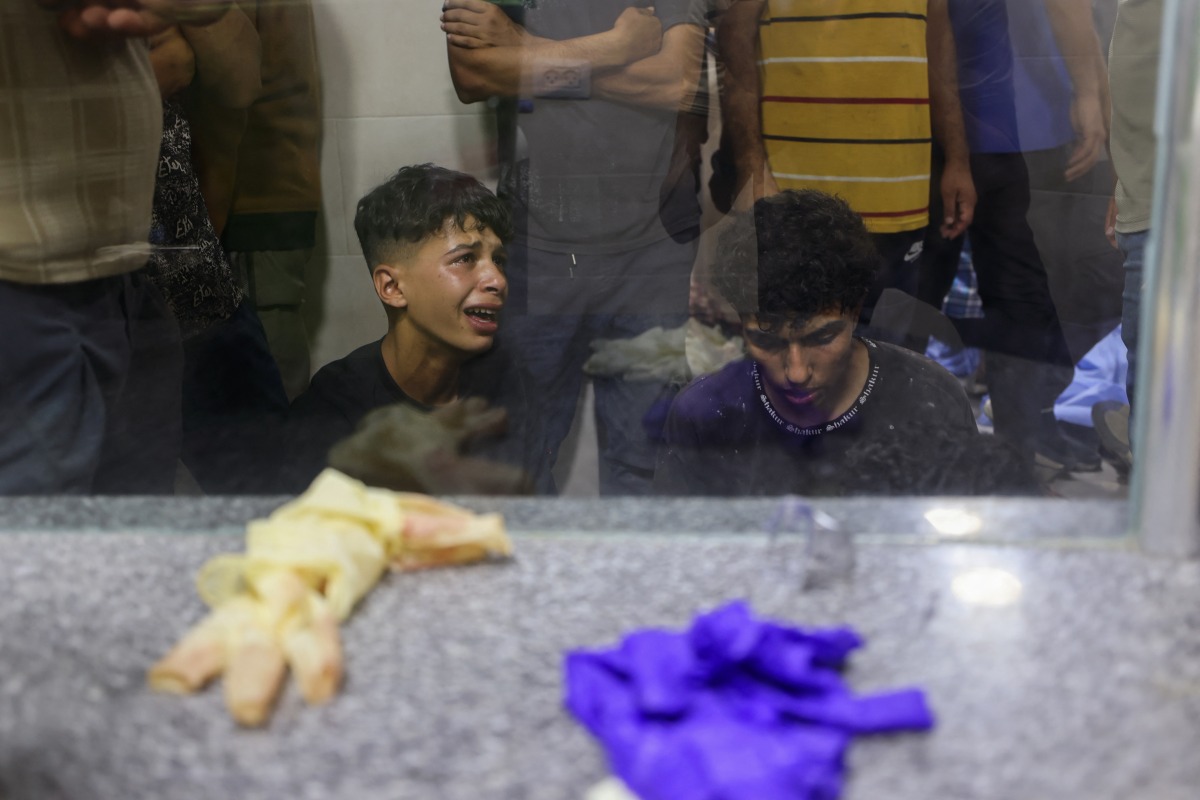 Palestinian youths mourn by the body of a relative killed in Israeli fire at a food aid distribution point set up by the privately-run Gaza Humanitarian Foundation (GHF) on the Salaheddin road, at Al-Awda hospital in the Nuseirat refugee camp in the central Gaza Strip on June 24, 2025. (Photo by Eyad BABA / AFP)
