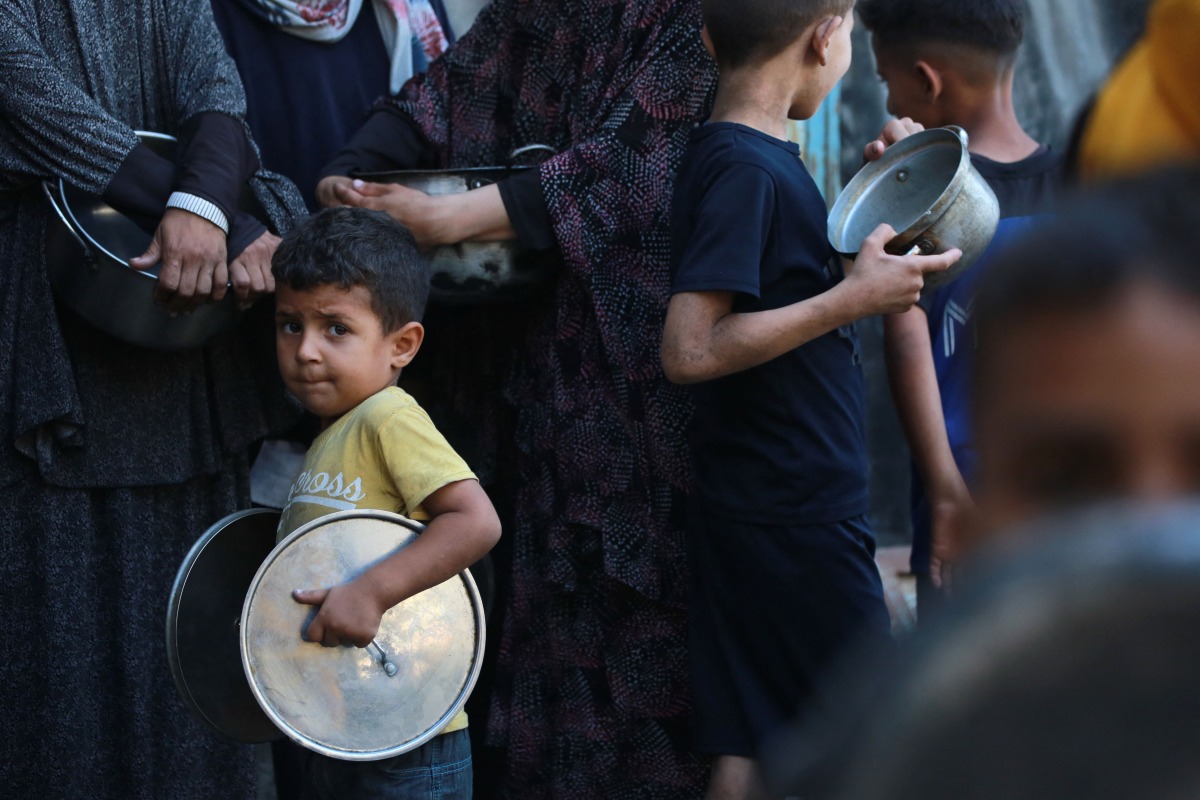 Palestinians line up to receive a hot meal at a food distribution point in Gaza City on June 27, 2025. Photo by BASHAR TALEB / AFP