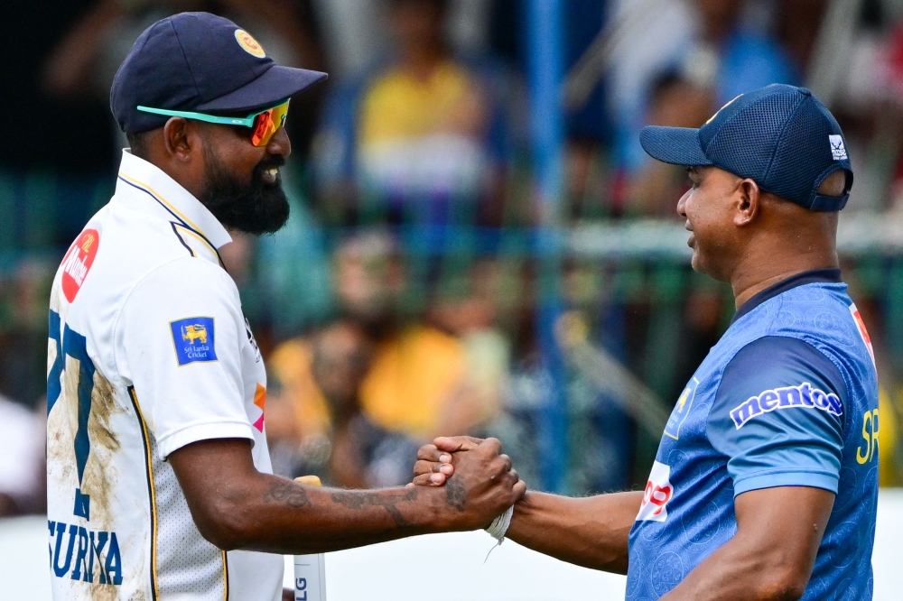 Sri Lanka's Prabath Jayasuriya (L) and coach Sanath Jayasuriya celebrate Sri Lanka's win in the end of fourth day of the second Test cricket match against Bangladesh at the Sinhalese Sports Club (SSC) in Colombo on June 28, 2025. (Photo by Ishara S. Kodikara / AFP)