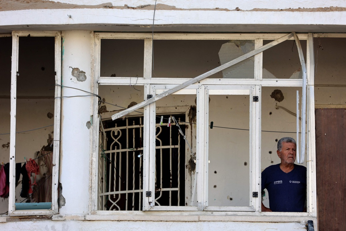 A Palestinian man stands at the glassless window of a home in the northern Al-Rimal neighborhood of Gaza City on June 28, 2025. Photo by Omar AL-QATTAA / AFP
