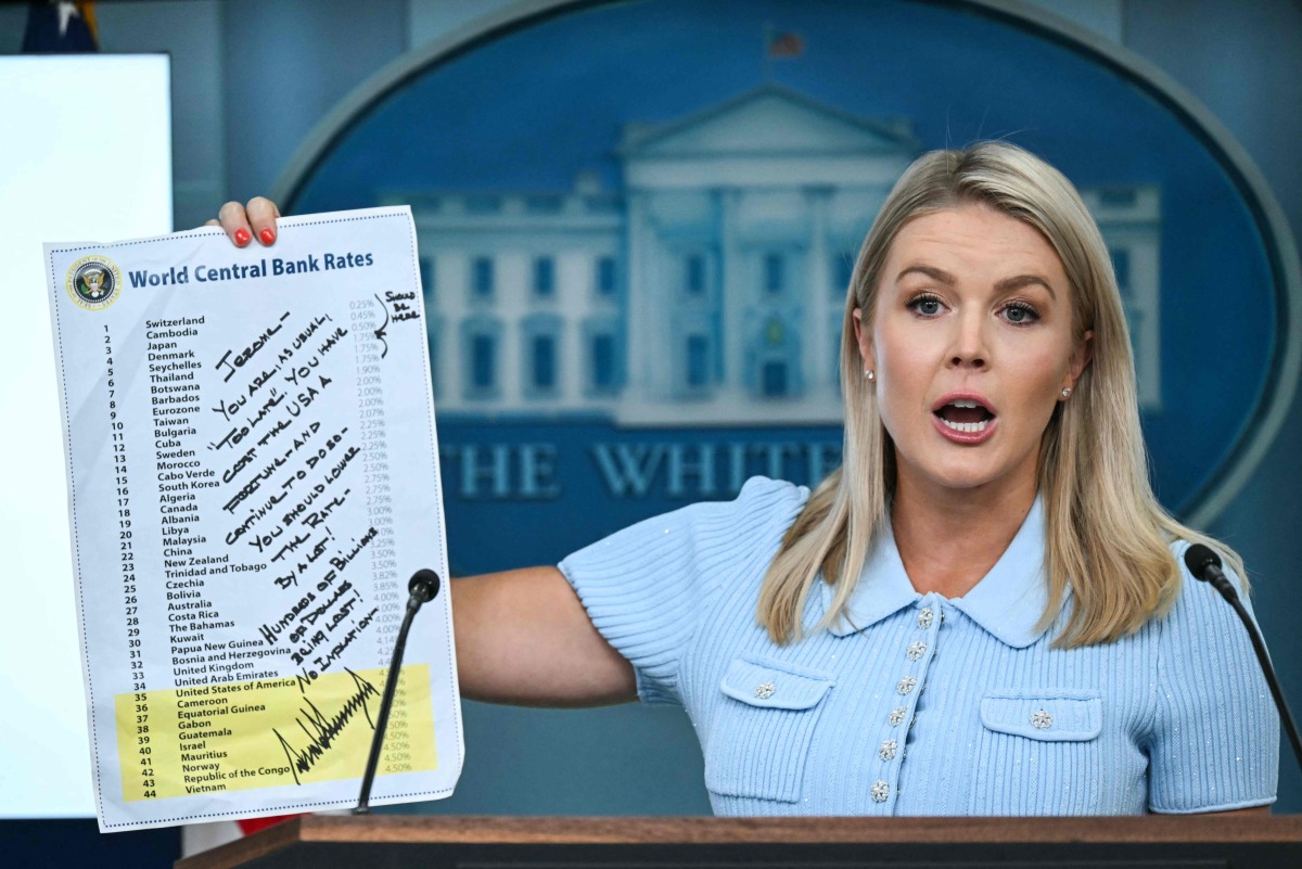 White House Press Secretary Karoline Leavitt, holding up a sheet showing global interest rates and a message from US President Donald Trump to Federal Reserve Chair Jerome Powell, speaks during the daily briefing in the Brady Briefing Room of the White House in Washington, DC, on June 30, 2025. (Photo by ANDREW CABALLERO-REYNOLDS / AFP)
