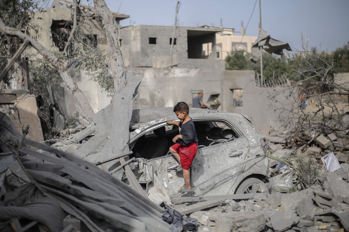 A Palestinian boy checks the wreckage of a car at the rubble of a residential house in Deir el-Balah in the central Gaza Strip on July 1, 2025. (Photo by Eyad BABA / AFP)

