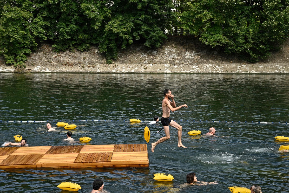 A swimmer jumps in the water at the Grenelle safe bathing site on the Seine river on its opening day, in Paris on July 5, 2025. (Photo by JULIEN DE ROSA / AFP)