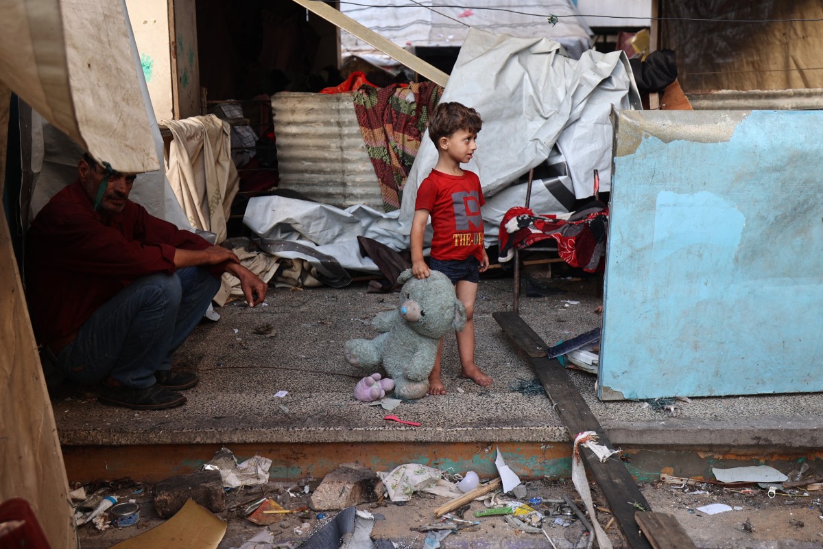 A Palestinian child holds a stuffed animal while standing at a school sheltering displaced Palestinians which was hit by an Israeli strike in the Al-Bureij camp in the central Gaza Strip on July 8, 2025. Photo by Eyad BABA / AFP