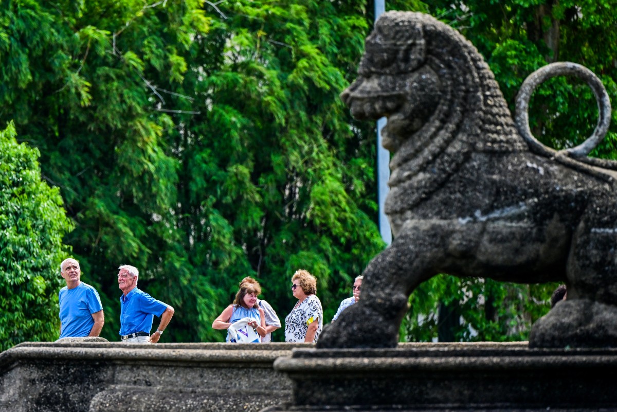 Tourists walk past a stone lion at the Independence Memorial Hall, built to commemorate Sri Lanka's independence from British rule, in Colombo on July 1, 2025. (Photo by Ishara S. KODIKARA / AFP)
