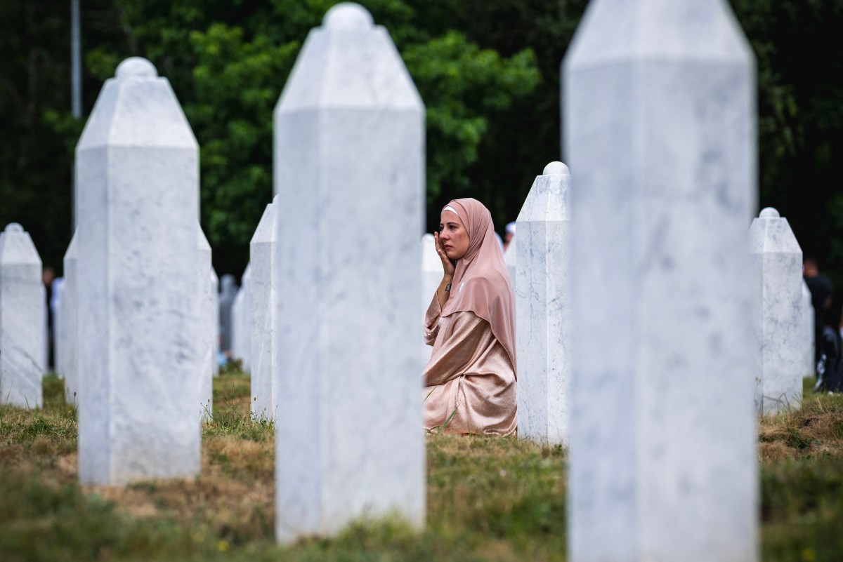 A woman reacts as she sits among gravestones at the memorial cemetery in the village of Potocari, near the eastern Bosnian town of Srebrenica, on July 11, 2025, on the 30th anniversary of the Srebrenica massacre. Photo by Andrej ISAKOVIC / AFP.