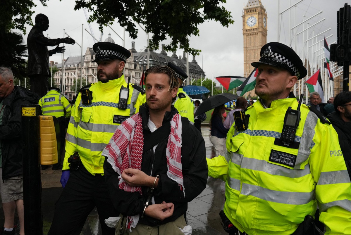 A protester is escorted away by police officers at a demonstration in support of the proscribed group Palestine Action calling for the recently imposed ban to be lifted, in Parliament Square, central London, on July 19, 2025. (Photo by CARLOS JASSO / AFP)

