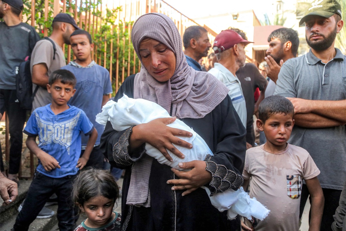 The mother of Yahya Fadi al-Najjar, an infant who died due to malnourishment, mourns as she holds his body during the funeral at Nasser Medical Complex in Khan Yunis in the southern Gaza Strip on July 20, 2025. (Photo by AFP)