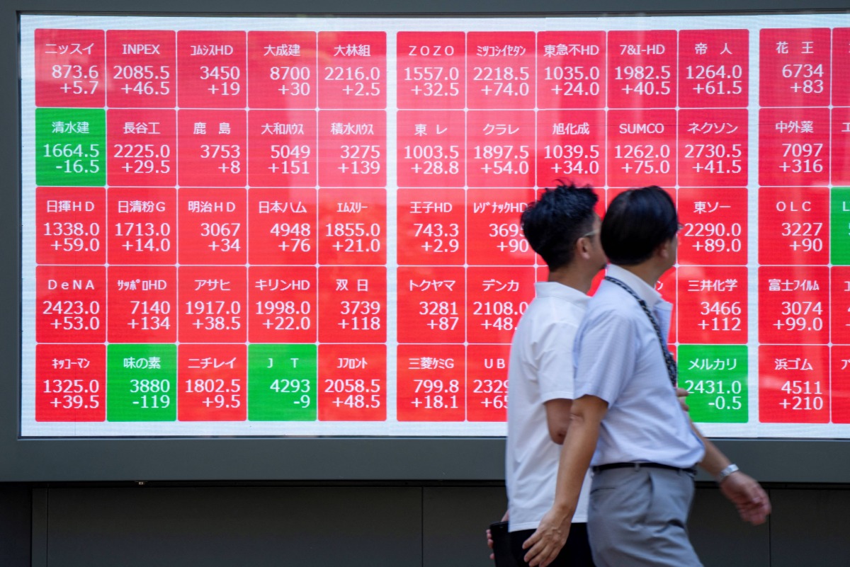 Pedestrians walk past an electronic quotation board displaying the Nikkei 225 stock prices on the Tokyo Stock Exchange in Tokyo on July 23, 2025. Photo by Kazuhiro NOGI / AFP.
