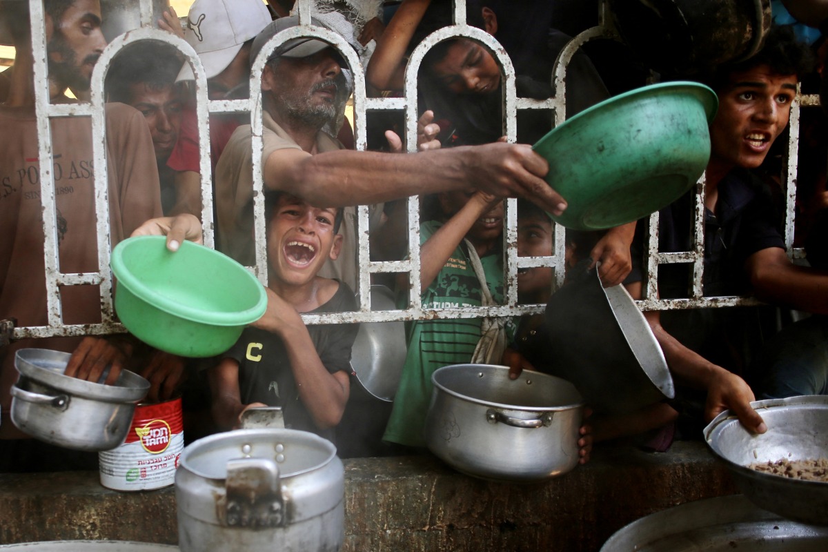 Palestinians shove to receive a hot meal at a charity kitchen in the Mawasi area of Khan Yunis in the southern Gaza Strip on July 22, 2025. Photo by AFP