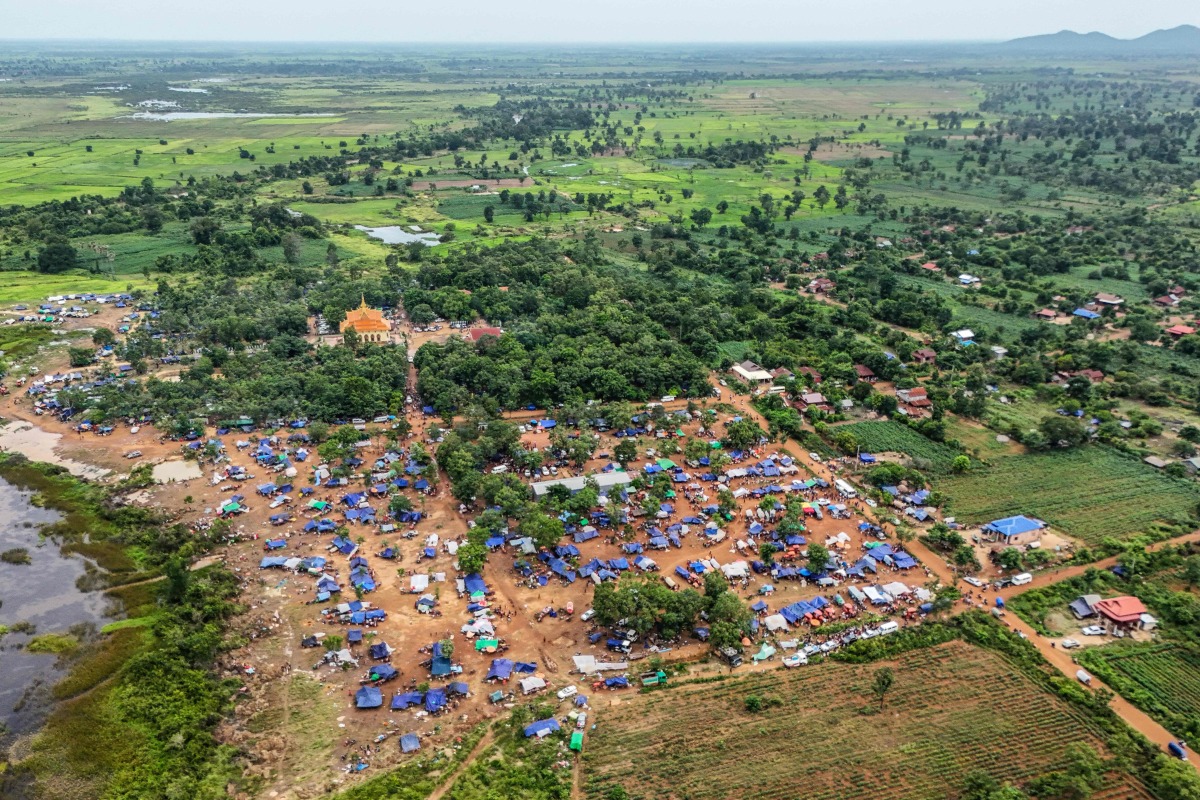 An aerial view shows people, who fled their homes near the border area between Cambodia and Thailand, taking shelter near a pagoda in Oddar Meanchey province on July 26, 2025. (Photo by Suy Se / AFP)
