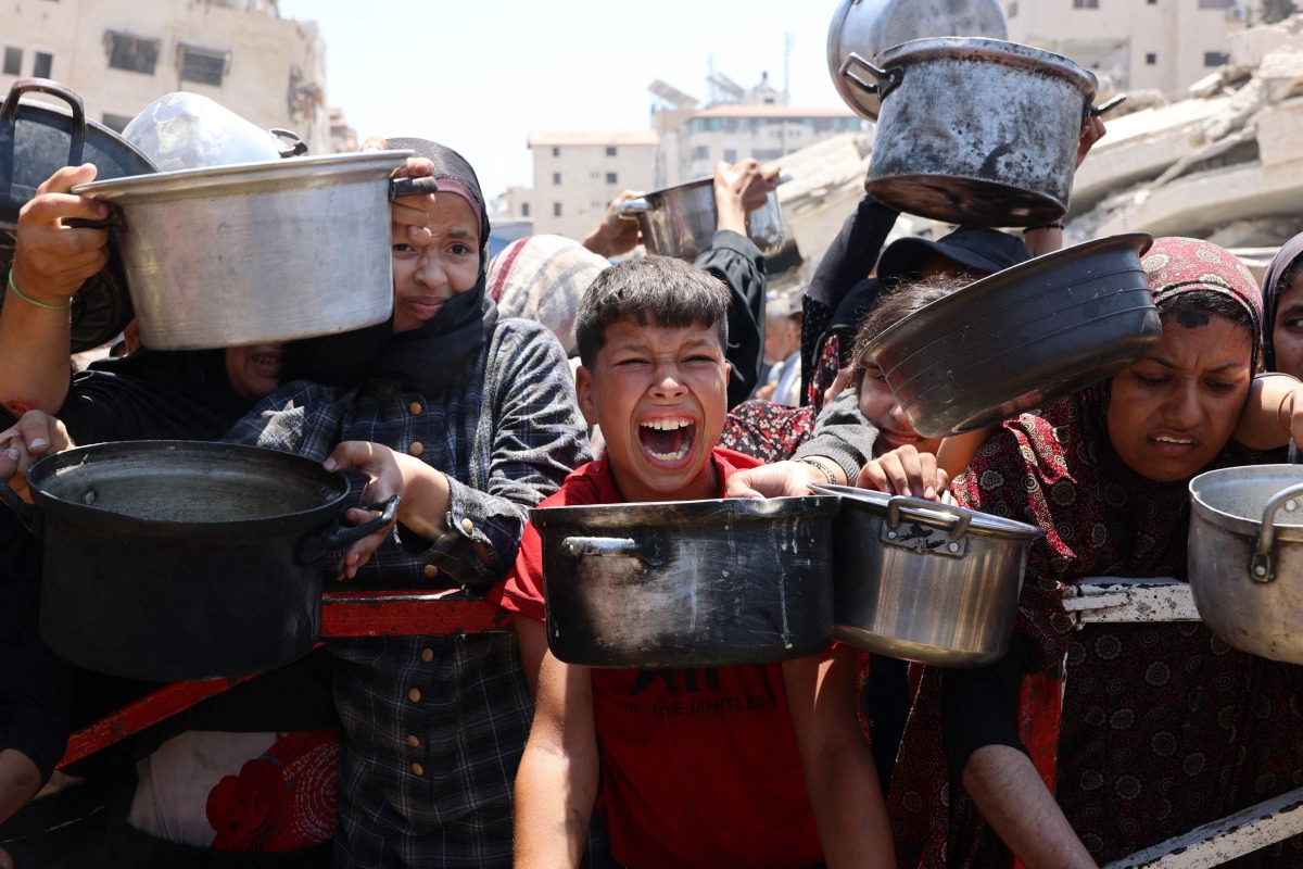 Palestinians crowd at a lentil soup distribution point in Gaza City in the northern Gaza Strip on July 27, 2025. (Photo by Omar AL-QATTAA / AFP)