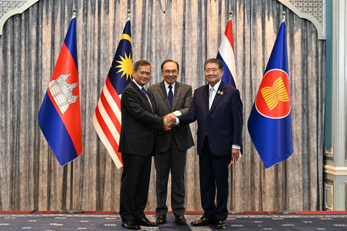 Malaysia's Prime Minister Anwar Ibrahim (C), Cambodia's Prime Minister Hun Manet (L) and Thailand's acting Prime Minister Phumtham Wechayachai (R) pose for photos as they shake hands following a press conference after talks on a possible ceasefire between Thailand and Cambodia in Putrajaya on July 28, 2025. (Photo by MOHD RASFAN / POOL / AFP)
