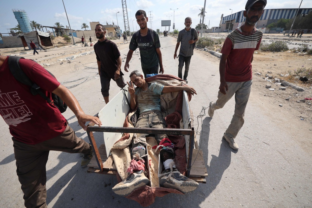 Palestinians transport a man, wounded as he waited for humanitarian aid at a GHF aid distribution point, at the entrance of the Bureij refugee camp in the central Gaza Strip on July 30, 2025. (Photo by Eyad BABA / AFP)