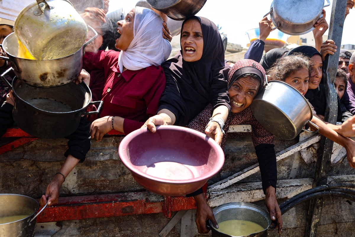 Palestinians receive lentil soup at a food distribution point in Gaza City on August 2, 2025. (Photo by Omar AL-QATTAA / AFP)
