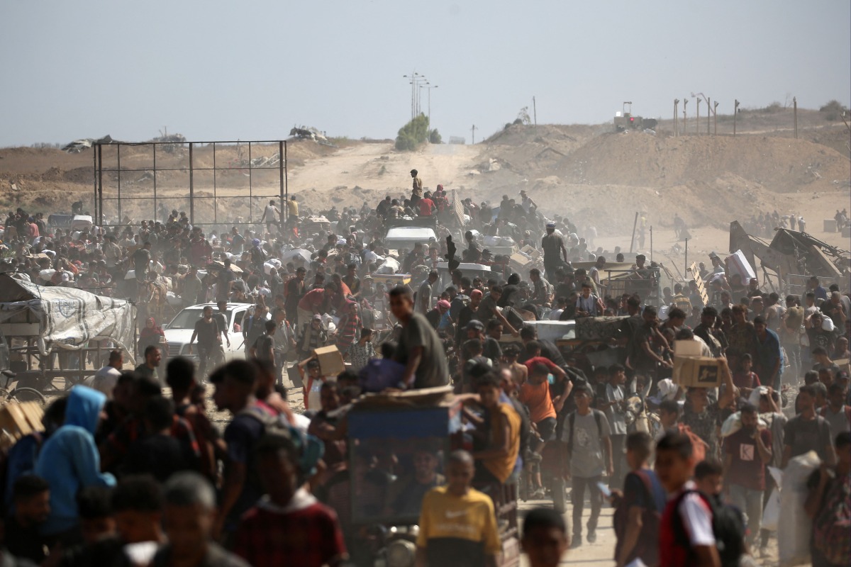 Palestinians leave a food distribution point run by the US and Israeli-backed Gaza Humanitarian Foundation (GHF) group with bags and wooden pallets, near the Netsarim corridor in the central Gaza Strip yesterday. (AFP)