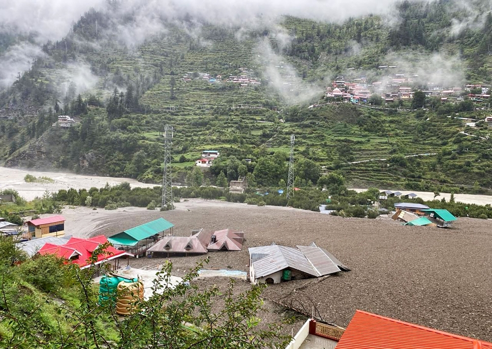 This handout photograph taken on August 5, 2025 and released by the Indian Army shows residential buildings partially submerged in sludge after a cloudburst caused a massive mudslide in India's Uttarakhand state. (Photo by Indian Army / AFP)