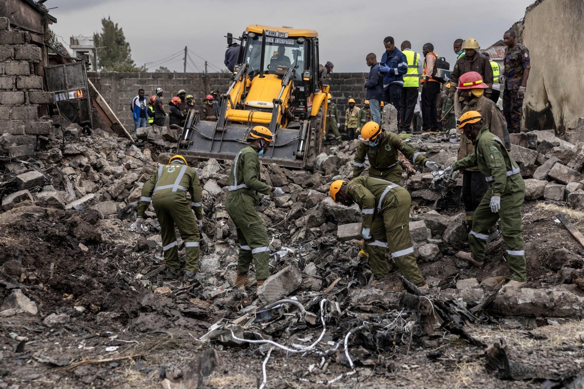 Rescuers work betwwen wreckage parts at a scene where a Kenyan medical plane crashed, killing at least 6 people, on the outskirts of Nairobi on August 7, 2025. (Photo by SIMON MAINA / AFP)
