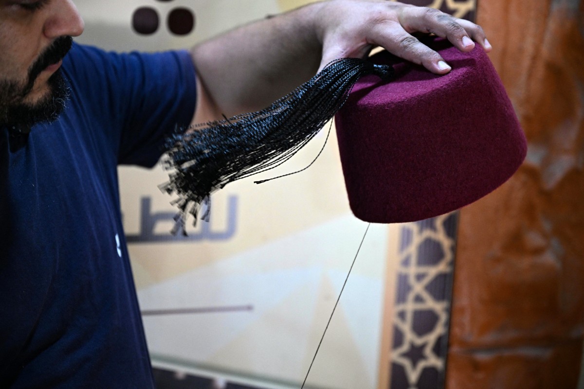 Lebanese craftsman Mohammed al-Shaar sews a tassel on a tarboosh, also known as 'fez', at his workshop in the northern Lebanese costal city of Tripoli on August 6, 2025. Photo by Joseph EID / AFP