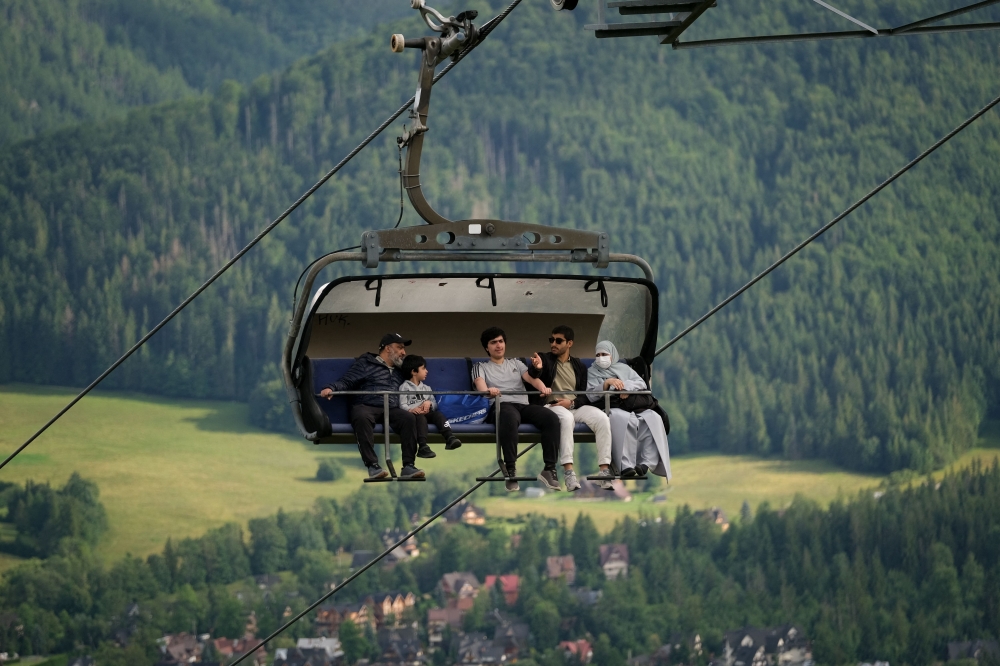 Tourists sit in a chairlift on the hill Gubalowka, a hill from which there is a view of Zakopane and the Tatra Mountains, on August 4, 2025. (Photo by Bartosz Siedlik / AFP) 
