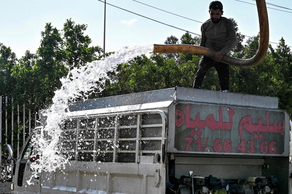 (Files) A man fills a tanker delivery truck with water from an underground water well distribution facility in Beirut on July 3, 2025. (Photo by Joseph Eid / AFP)