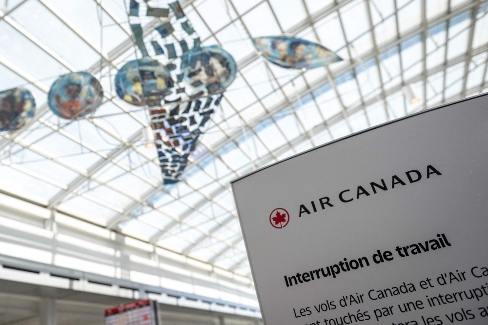 An Air Canada labour dispute sign is seen at the Pierre-Elliot Trudeau Airport in Montreal, Quebec, Canada, on August 15, 2025. (Photo by Andrej Ivanov / AFP)