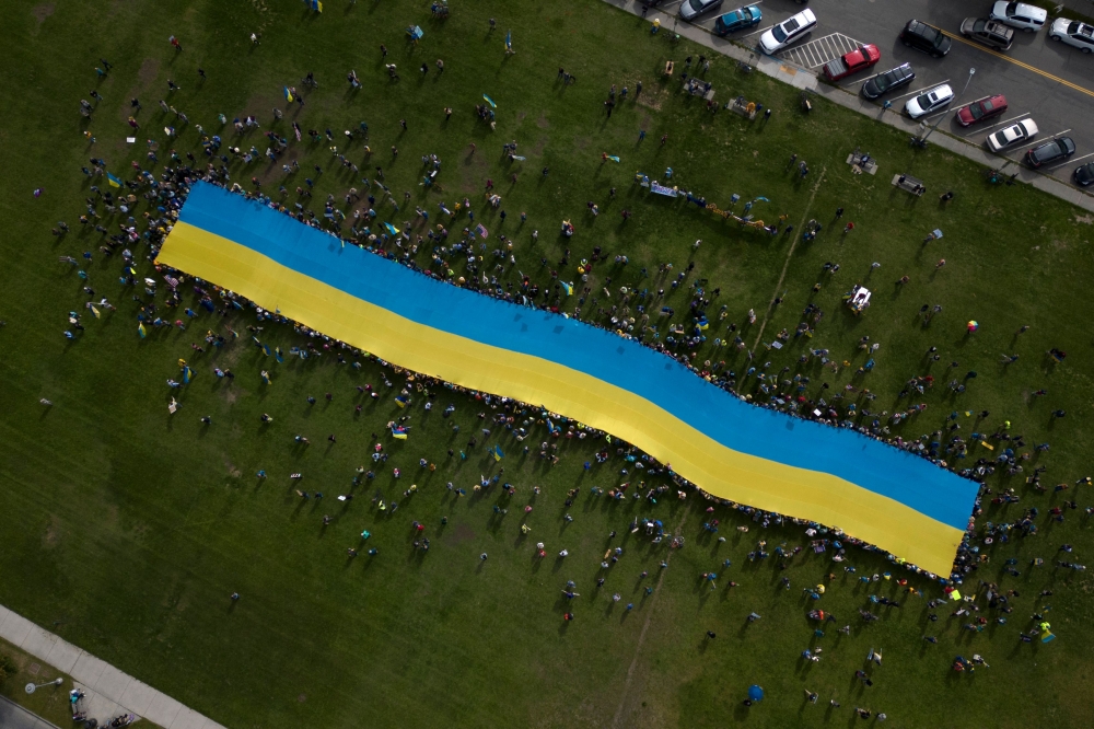 This aerial view shows protesters holding a giant Ukrainian flag in Anchorage, Alaska, on August 15, 2025 during a US-Russia summit. (Photo by Daphné Lemelin / AFP)