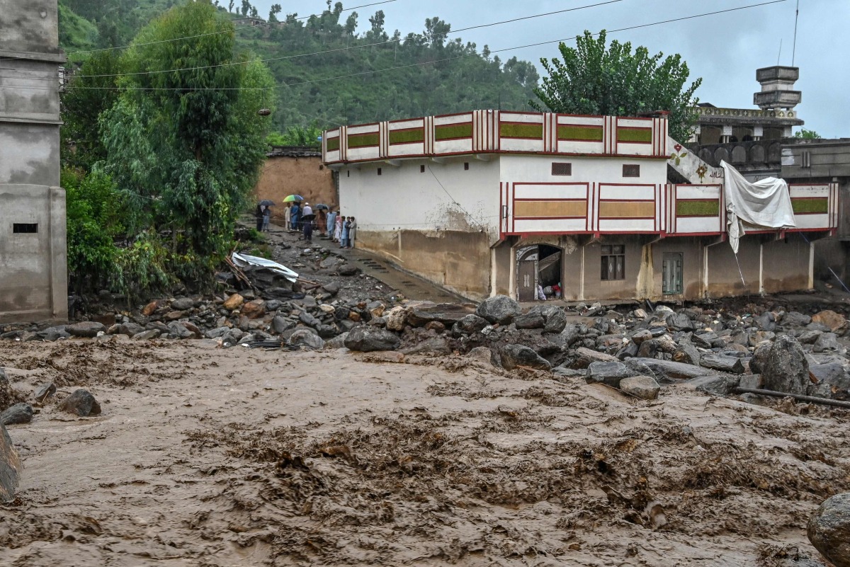 Villagers (center, L) stand near a building as floodwater levels rise in the Buner district of Pakistan's Khyber Pakhtunkhwa province on August 18, 2025. Photo by Abdul MAJEED / AFP