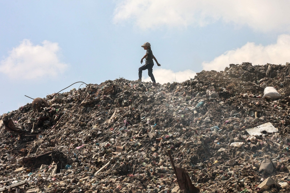 A Palestinian girl searches for things to rescue at a garbage waste dump in Gaza City on August 18, 2025. (Photo by Omar Al-Qattaa / AFP)