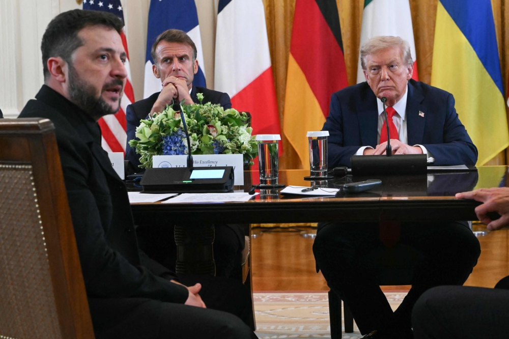 (L/R) Ukrainian President Volodymyr Zelensky speaks as French President Emmanuel Macron and US President Donald Trump listen during a meeting with European leaders in the East Room of the White House in Washington, DC, on August 18, 2025. (Photo by Andrew Caballero-Reynolds/ AFP)
