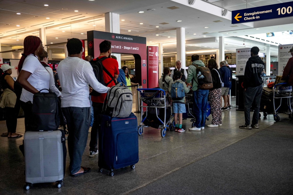 Passengers queue to check in as Air Canada flights are slated to resume as early as this evening at Pierre-Elliott Trudeau Airport in Montreal, Quebec, on August 19, 2025.  (Photo by Andrej Ivanov / AFP)