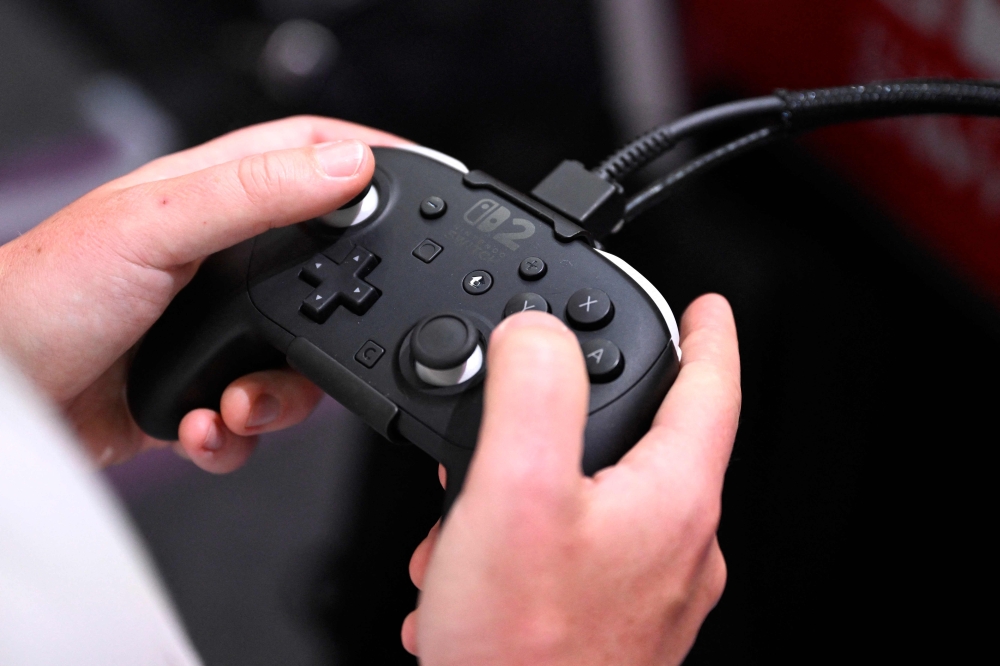 A gamer holds a controller, at the Nintendo Switch 2 booth, during the Gamescom video games trade fair at the Trade Fair Center in Cologne, western Germany on August 20, 2025. (Photo by Ina Fassbender / AFP)