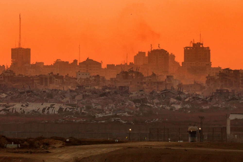 This picture taken from a position on Israel's border with the Gaza Strip shows destroyed buildings in the besieged Palestinian territory at sunset on August 21, 2025. (Photo by Jack Guez / AFP)