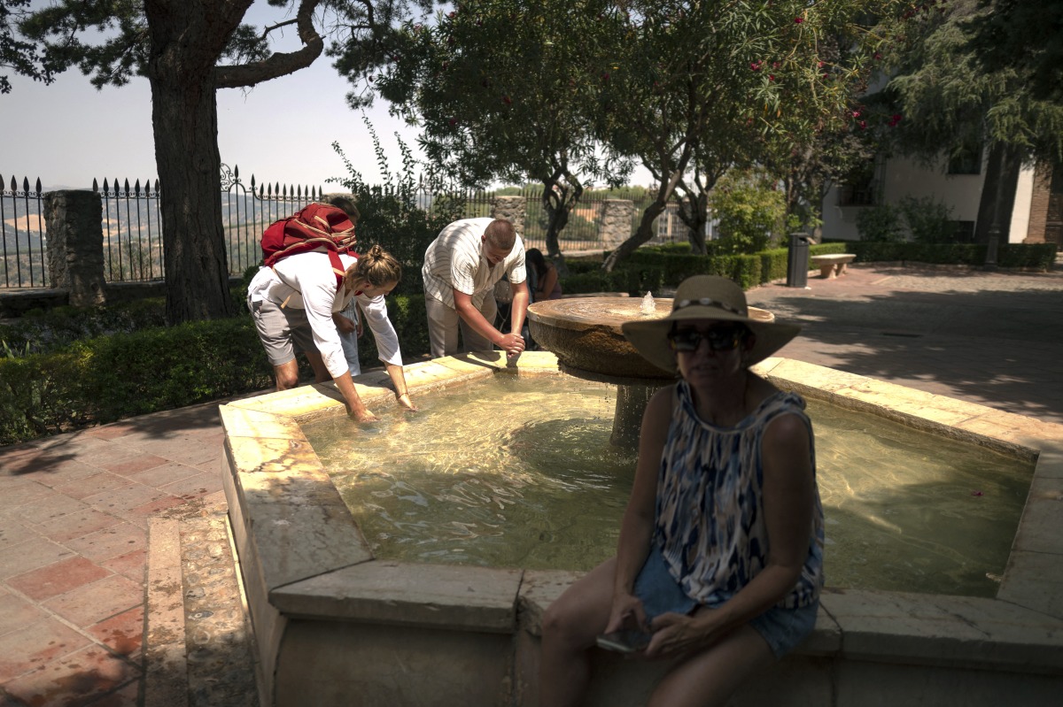 Tourists cool off near a fountain during a heatwave in Ronda on August 17, 2025. Photo by JORGE GUERRERO / AFP