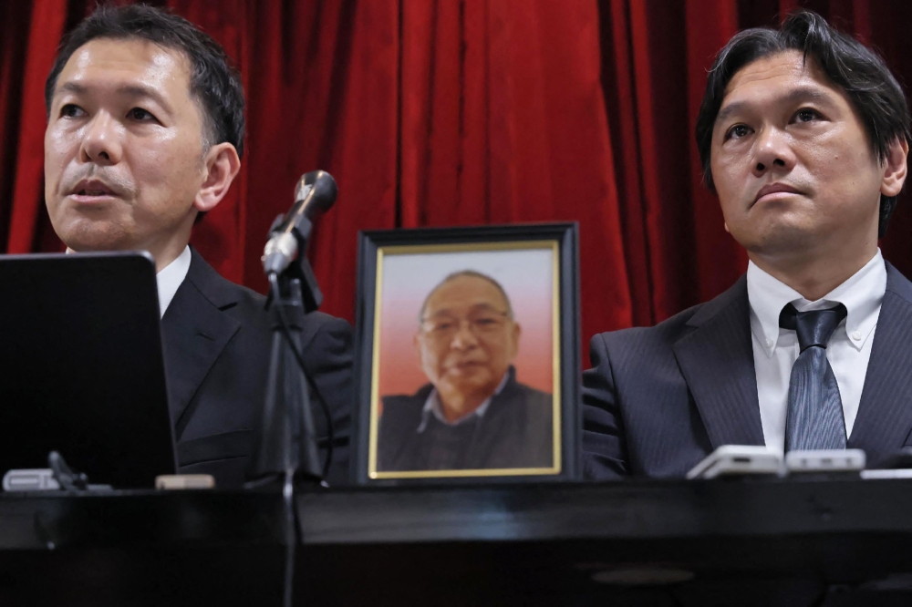 A portrait of the late Shizuo Aishima (C) is seen as his sons hold a press conference in Yokohama on August 25, 2025. (Photo by Japan Pool / JIJI PRESS / AFP) 