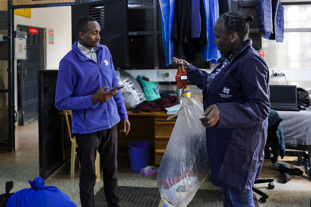 A resident uses digital credit earned from delivering plastic waste to a Human Needs Project (HNP) collection point to pay for laundromat services in the Kibera informal settlement of Nairobi. (Photo by Tony Karumba / AFP)