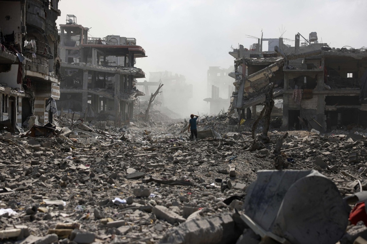 A Palestinian youth stands on a street strewn with rubble following an explosion in the Saftawi neighbourhood, west of Jabalia in the northern Gaza Strip on August 25, 2025. Photo by BASHAR TALEB / AFP