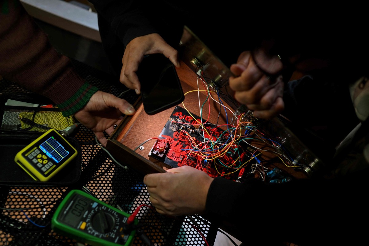 Men repair a disused computer during the 3rd Federal Cyberciruja Meeting in Buenos Aires, on August 16, 2025. Photo by Luis ROBAYO / AFP
