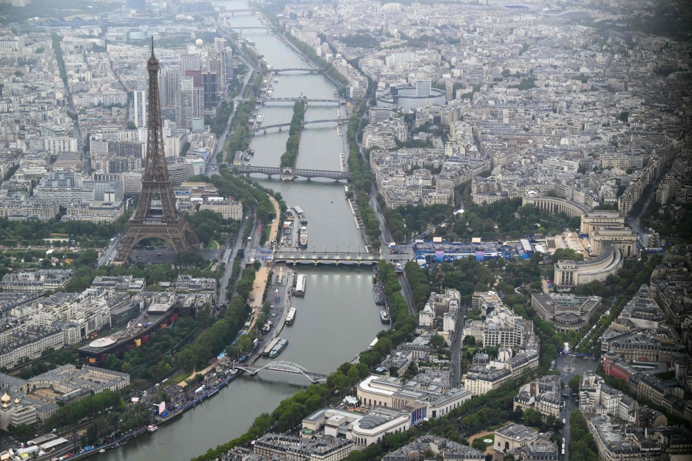 A photograph taken from an helicopter on July 26, 2024 shows an aerial view of the Eiffel Tower along the Seine river during the opening ceremony of the Paris 2024 Olympic Games in Paris. (Photo by Lionel BONAVENTURE / POOL / AFP)

