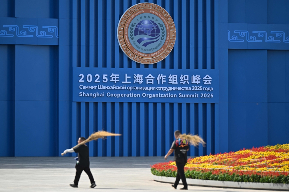 Cleaning staff work in front of the Meijiang Convention and Exhibition Center ahead of the Shanghai Cooperation Organisation (SCO) Summit in Tianjin on August 30, 2025. (Photo by Pedro Pardo / AFP)