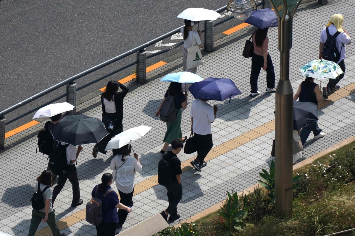 People with umbrellas walk in the scorching sun in Tokyo on September 1, 2025. (Photo by Kazuhiro NOGI / AFP)