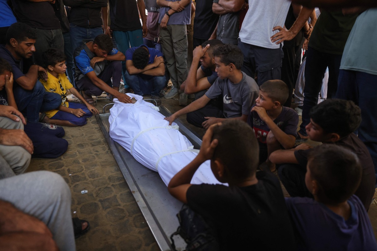 Palestinians mourn by the shrouded body of a relative killed in Israeli strikes on Gaza City the previous night, at Al-Shifa hospital on September 1, 2025. (Photo by BASHAR TALEB / AFP)
