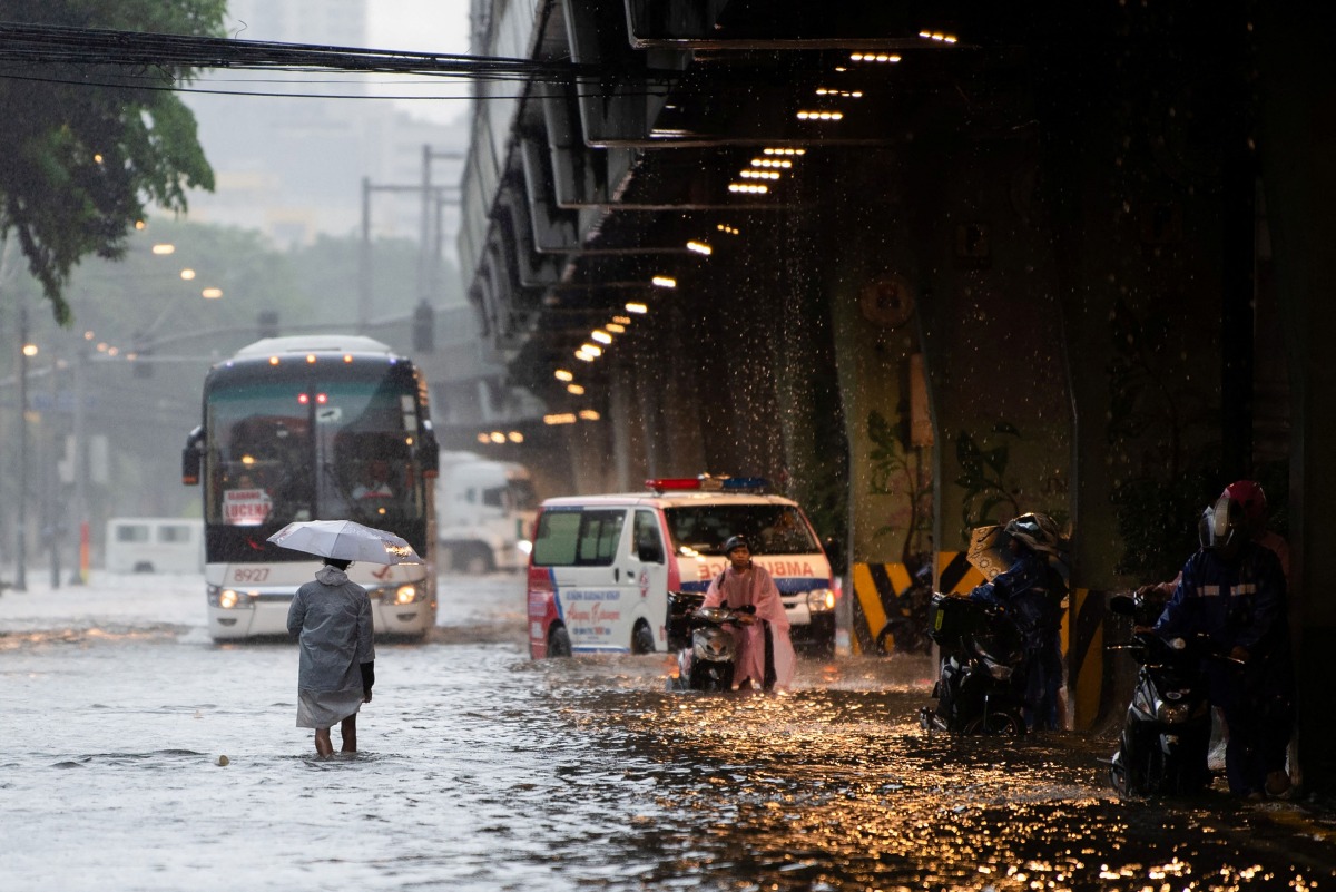 In this photo taken on July 22, 2025, pedestrians wade through a flooded street caused by heavy rains in Manila. Photo by Ted ALJIBE / AFP