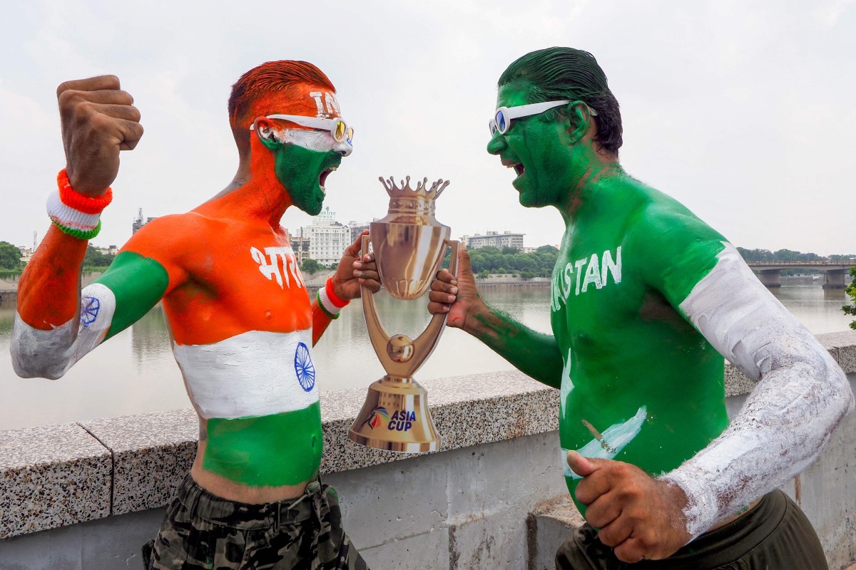 Fans with their bodies painted in national flags of India (L) and Pakistan pose in Ahmedabad on September 13, 2025, with a replica of the Asia Cup 2025 trophy on the eve of the Twenty20 international cricket match between India and Pakistan in Dubai. (Photo by Sam PANTHAKY / AFP)
