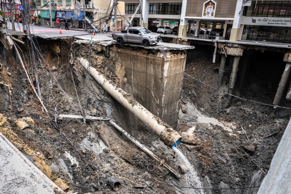 A vehicle is seen on the edge of a hole in the ground after a road collapsed near a hospital in Bangkok on September 24, 2025. (Photo by Chanakarn Laosarakham / AFP)