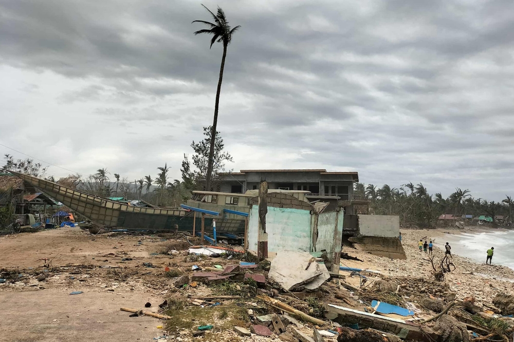A fishing boat is washed ashore near houses in Calayan island, Cagayan province on September 23, 2025, a day after Super Typhoon Ragasa hit the island.  (Photo by Cristy Gaffud / AFP)