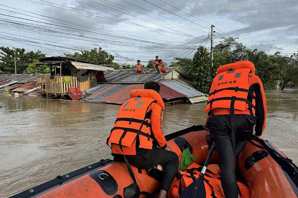 This handout photo taken on September 26, 2025 and released on September 27 by the Philippine Coast Guard shows coast guard personnel rescuing residents from their flooded house at the height of Severe Tropical Storm Bualoi, at a village in Ormoc City, Leyte province. (Photo by Handout / Philippine Coast Guard (PCG) / AFP)