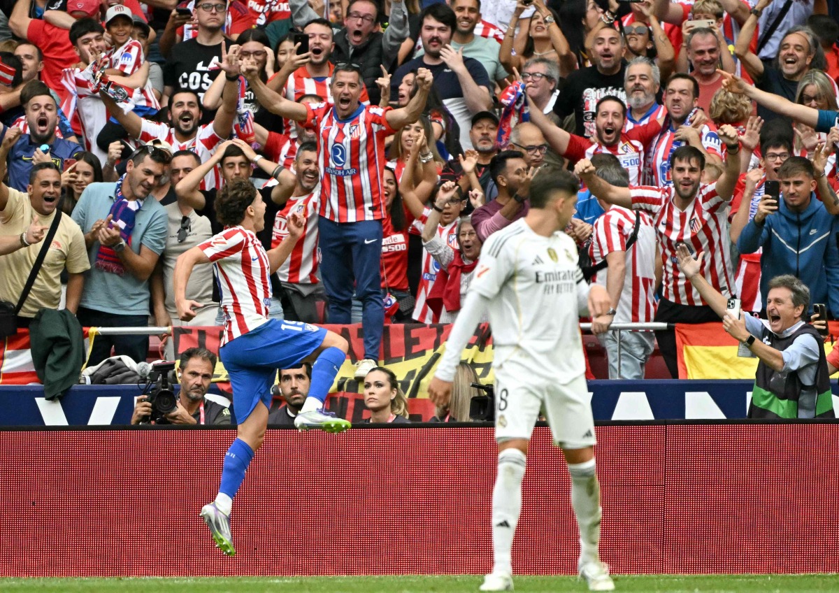Atletico Madrid's Argentine forward #19 Julian Alvarez celebrates with supporters scoring his team's fourth goal in spite of Real Madrid's Belgian goalkeeper #01 Thibaut Courtois during the Spanish league football match between Club Atletico de Madrid and Real Madrid CF at the Metropolitano stadium in Madrid on September 27, 2025. (Photo by Javier SORIANO / AFP)
